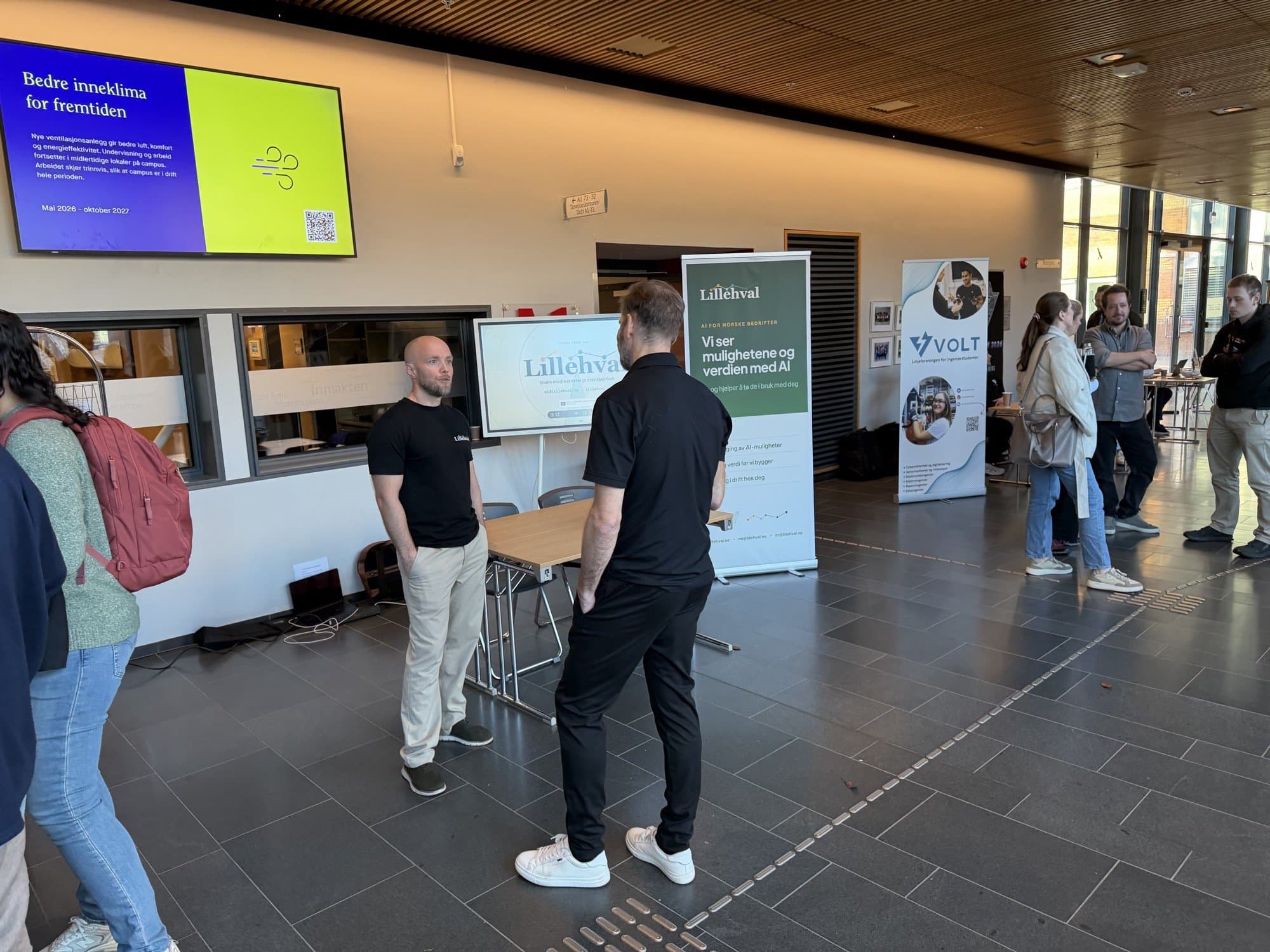 Samtale ved Lillehvals stand, med roll-upen til linjeforeningen VOLT ved siden av.